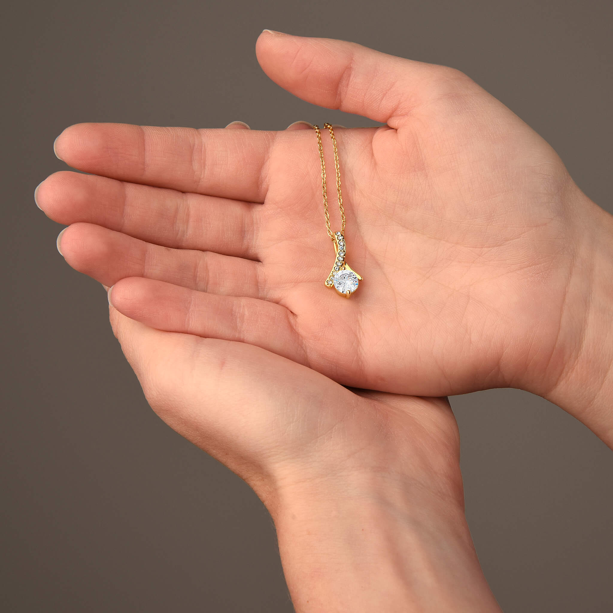Woman's hands holding dainty gold pendant necklace