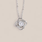 14k white gold-plated Radiance necklace featuring a round-cut cubic zirconia crystal surrounded by intertwining loops that resemble a Celtic knot with embedded crystals.